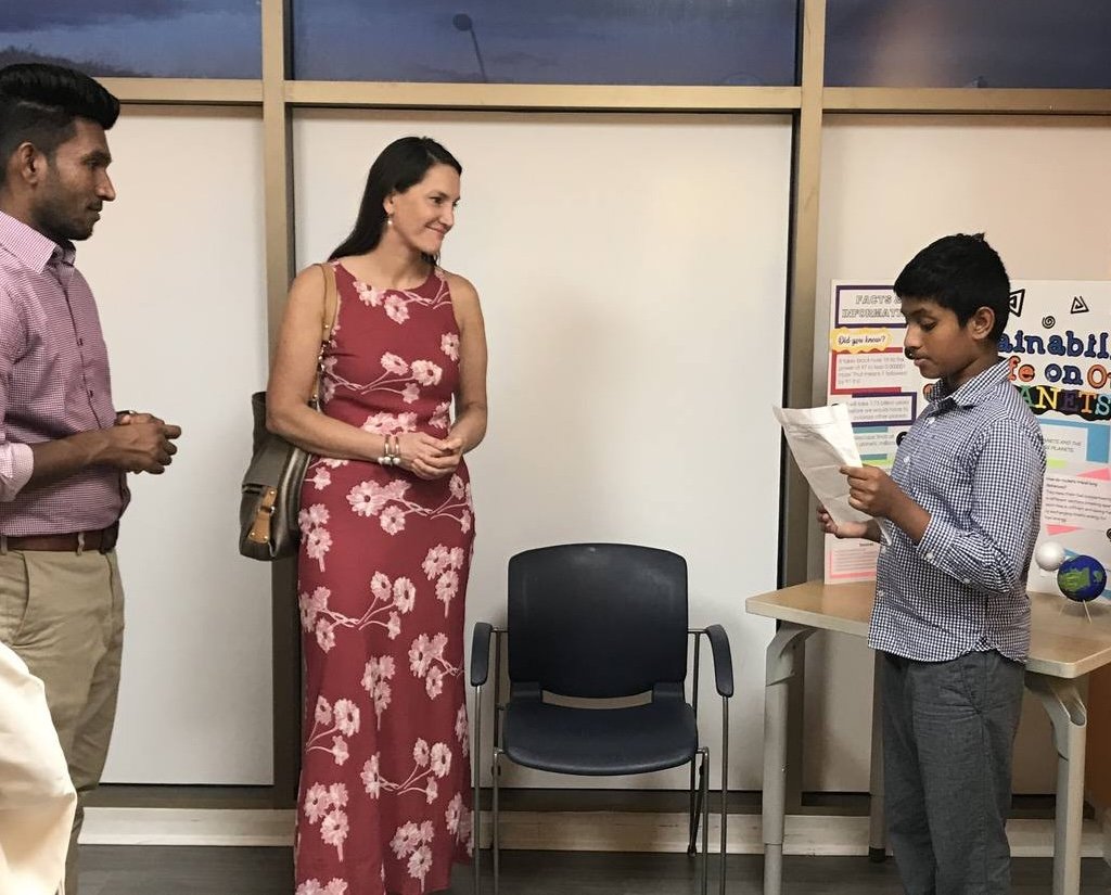 Marisa Sterling listening to a student present a sustainability project at a school event